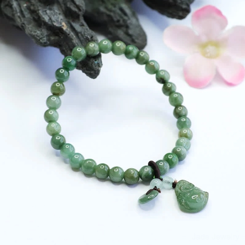 Natural cyan jade Buddha bracelet styled with decorative dark rock and pink flowers, showing detail of carved Buddha charm and accent jade beads