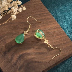 Back view of cyan jade drop earrings displayed on wooden surface, showing the reverse side of the jade setting and gold hardware, detailed side perspective