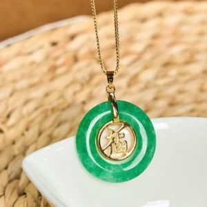 Close-up detail of cyan jade peace buckle pendant with gold-tone fu character charm and chain