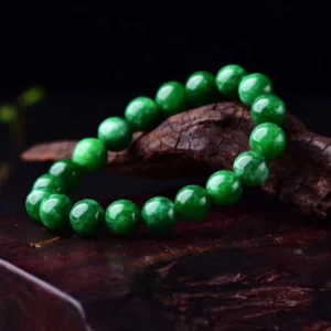 Cyan jade bead bracelet overhead view showing smooth round polished jade beads with natural veining on dark wooden surface