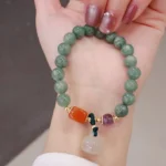 Cyan jade lotus charm bracelet with amethyst and chalcedony beads, held in hand against neutral background