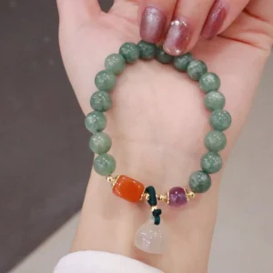 Cyan jade lotus charm bracelet with amethyst and chalcedony beads, held in hand against neutral background