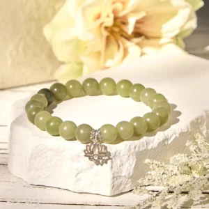 Green jade beaded bracelet with silver lotus accent shown at three-quarter angle with dried flowers, jade luck charm