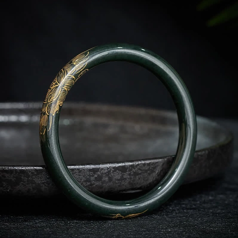 Cyan jade lotus koi fish bangle bracelet with gold gilded patterns, side view on dark ceramic surface