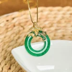 Cyan jade peace buckle necklace with gold flower clasp pendant, front view on jute mat