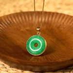 Cyan jade peace buckle necklace with gold bezel - artisan handcrafted pendant on wooden tray with natural styling