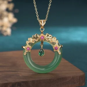 Natural cyan jade round pendant necklace with gold filigree setting and pink gemstone accents on wooden display