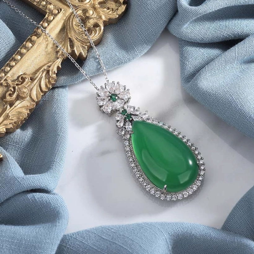 Cyan jade drop pendant necklace from top-down angle, displaying silver-tone metal filigree setting and delicate matching chain