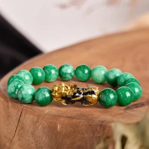 Cyan jade pixiu wealth bracelet with gold-black enamel charm on wooden display, top-down view