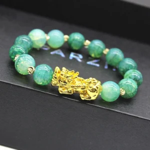 Handmade cyan jade beads with gold-plated Pi Xiu charm on luxury display tray showing detail and craftsmanship