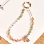 Cyan jade and clear quartz beaded phone lanyard with rose gold hardware, flat lay desktop view