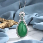 Cyan jade teardrop pendant necklace with pavé stone setting, front close-up view showing luminous green jade stone encircled by delicate gems