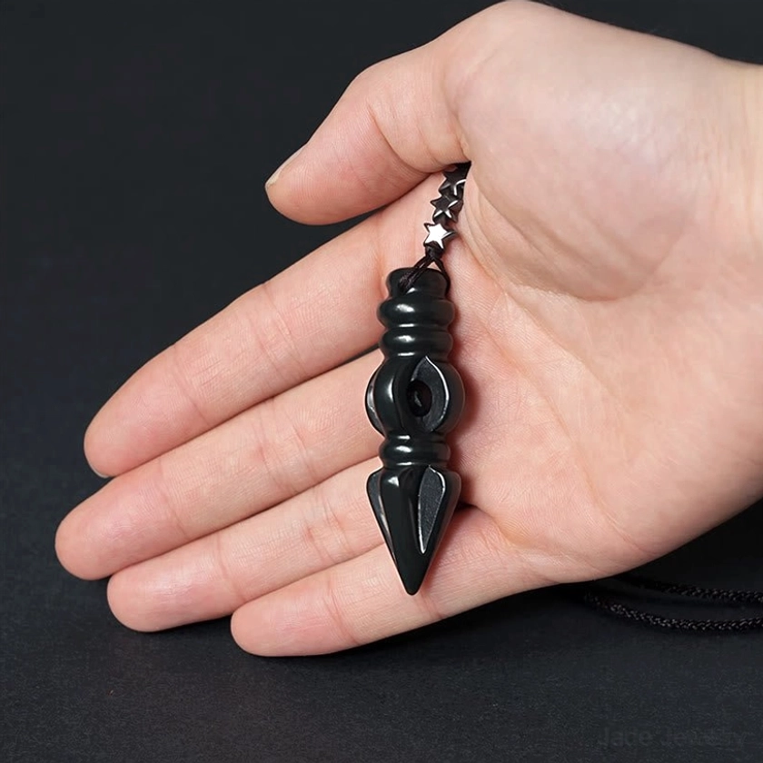 Hetian cyan jade Vajra Dorje pendant held in human palm showing actual size scale, glossy deep jade finish, and intricate carved details