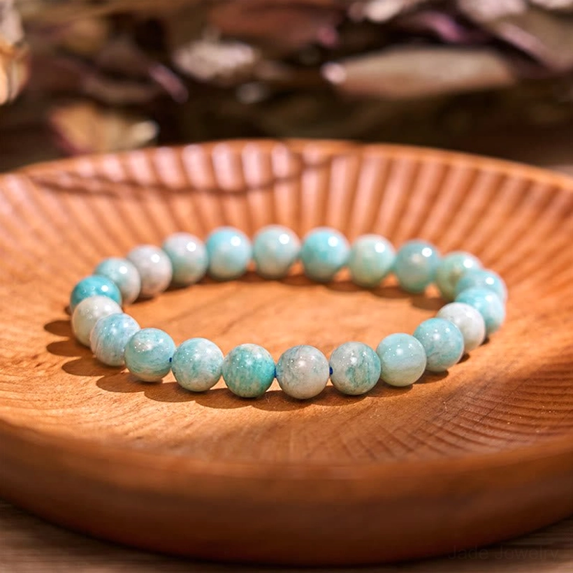 Dark amazonite jade balance bracelet flat lay on wooden plate, gradient blue-green to warm beige round polished beads