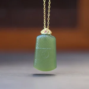 Dark green Hetian jade Om pendant necklace with engraved sacred symbol and 925 sterling silver bail, front view on wooden table