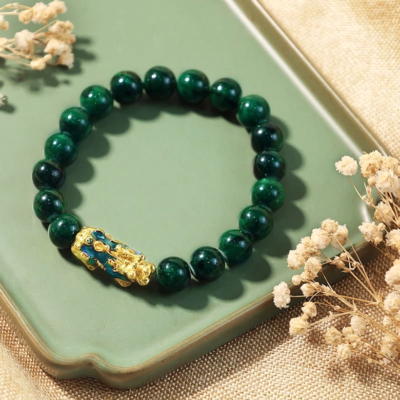 Dark green jade Pixiu fortune bracelet flat lay on green tray with dried flowers feng shui styling