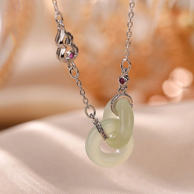 Silver double jade hoop necklace with light green jade and gem-set gourd charm flat lay