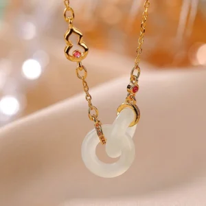 Double jade hoop necklace with gold plated chain and red gem gourd charm, flat lay close-up