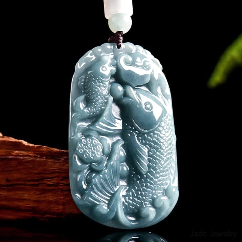 Double koi fish jade pendant carved on premium blue-grey natural jade, front overhead display view on wooden stand with beaded rope necklace, showcasing intricate fish and lotus relief carving detail
