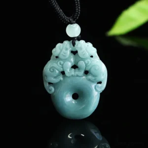 Double Pixiu jade peace buckle pendant necklace in blue-green jade, front view with black cord on dark reflective background