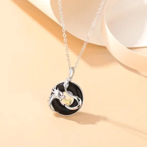 Dragon black onyx peace buckle necklace in 925 sterling silver hanging from beige ribbon, frontal view displaying intricate engraved dragon design and natural black gemstone