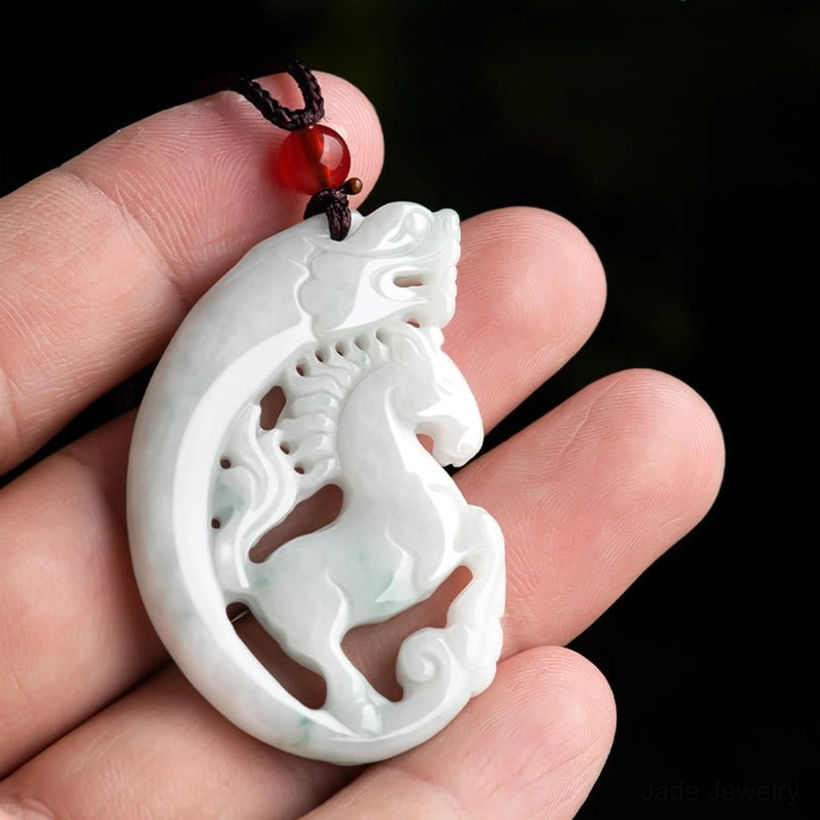Hand-held dragon horse jade pendant showing actual size and scale in palm, carved details visible with brown cord and red accent bead