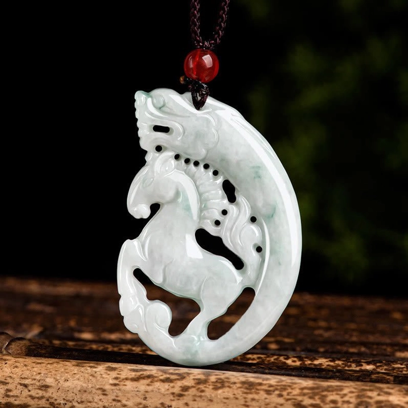 Dragon horse jade pendant necklace carved with intricate hollow design, displayed on wooden stand with brown rope cord and red bead