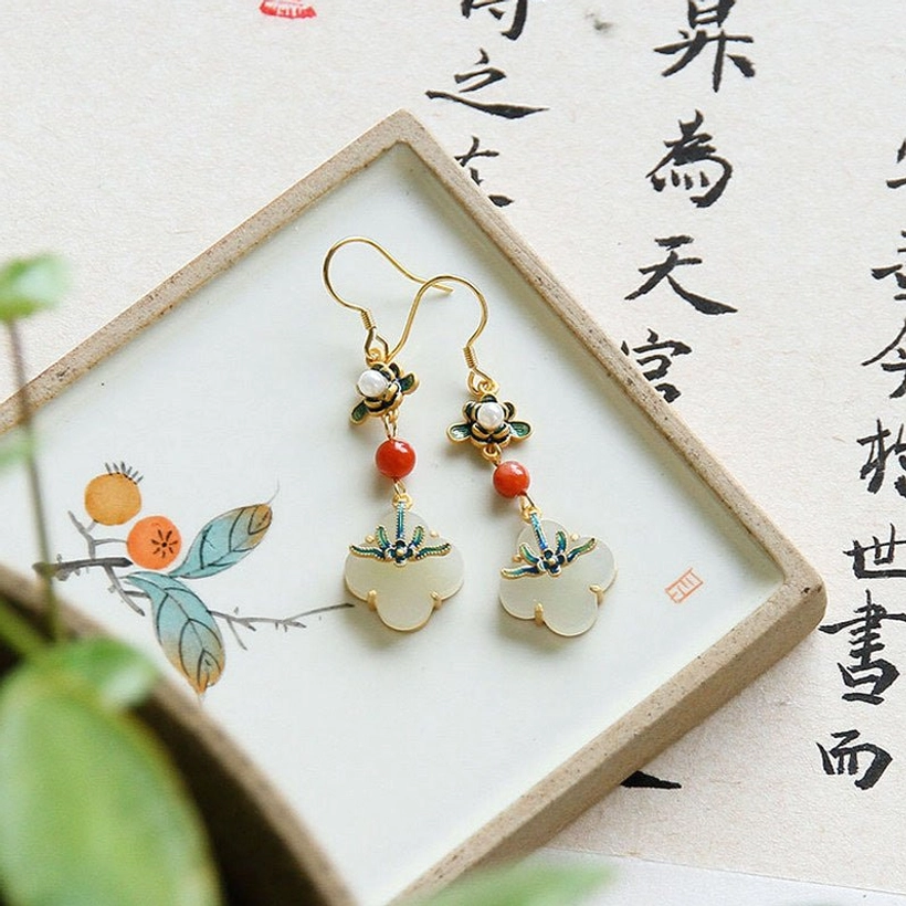 Four leaf clover jade earrings with gold hardware and red agate bead on artistic background