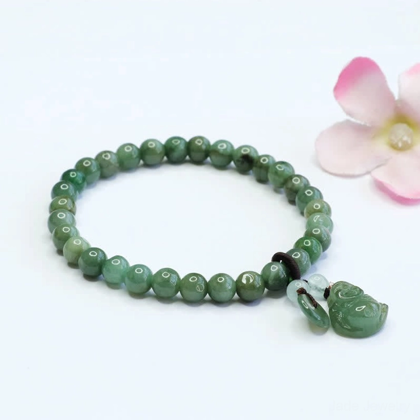 Complete jade bead strand with hand-carved Laughing Buddha pendant and extra jade accent charm on pink flower background