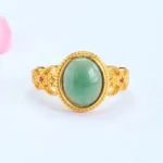 Gold filigree jade ring with red gem accents front view showing oval jade stone centerpiece