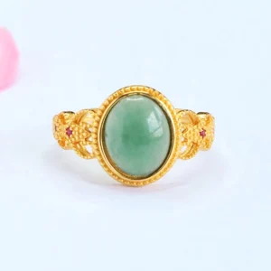 Gold filigree jade ring with red gem accents front view showing oval jade stone centerpiece