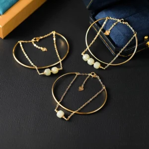 Multiple gold plated jade bangle bracelets flat lay featuring heart charm pendant on black leather surface