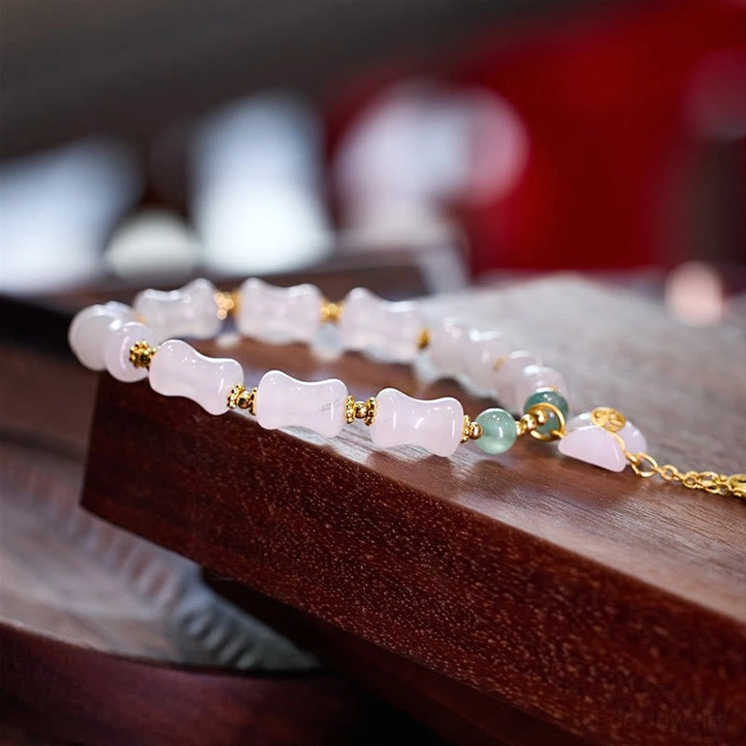 Full view of white golden silk jade bracelet with bamboo beads, green aventurine accents, and gold toggle clasp