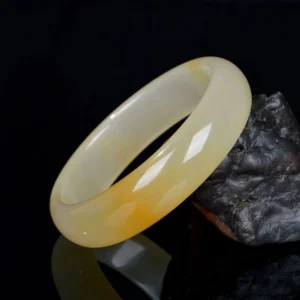 Natural Golden Silk Jade bangle showing authentic color veining and stone characteristics from front oblique angle