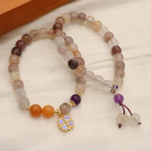 Pair of golden silk jade wealth bracelets flat lay on wooden surface, featuring earth-tone beads and matching flower charm