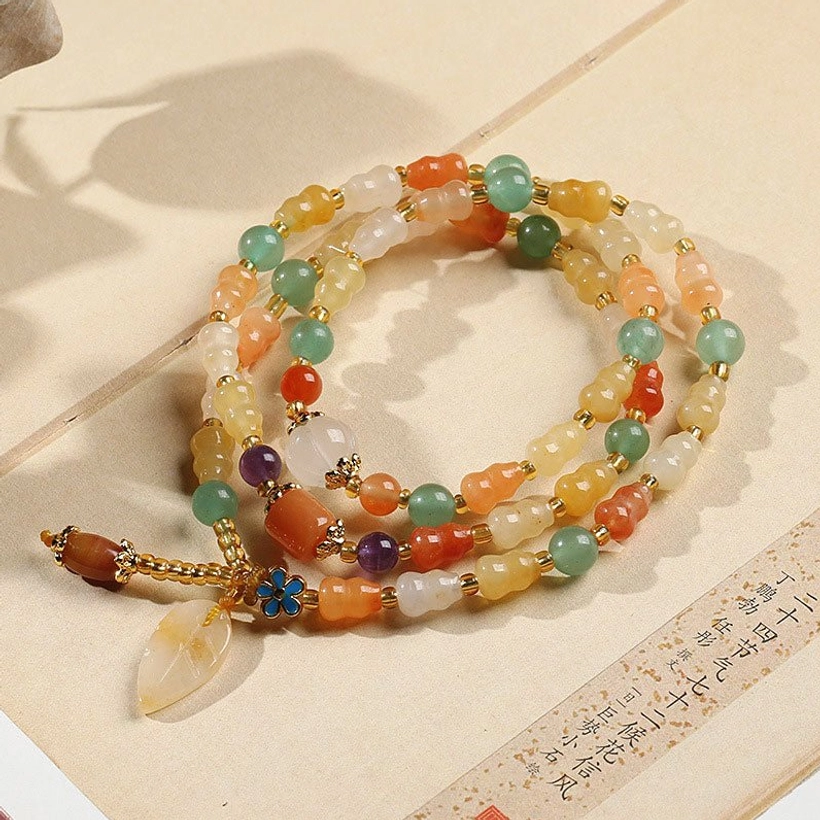 Golden Silk Jade Gourd Bracelet - Close-up detail of natural jade beads with gold spacer accents and enamel flower