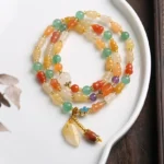 Golden Silk Jade Gourd Wealth Bracelet - Multi-strand beaded design with gourd pendant on white ceramic plate