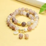 Golden Silk Jade double layer peace buckle bracelet overhead flat lay with jade beads, gold spacer details, and dangling charm on warm desktop