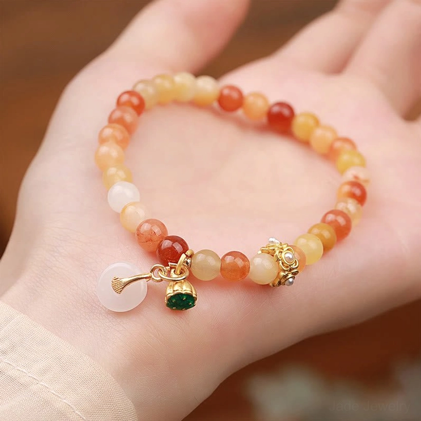 Golden silk jade peace buckle bracelet worn on wrist showing mixed warm-white jade beads with red accent and gold hardware