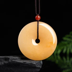 Golden silk jade peace buckle pendant necklace front view on dark background with natural stone