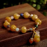 Golden Silk Jade Pixiu Wealth Bracelet with pumpkin-shaped yellow jade beads and gold hardware flat lay view