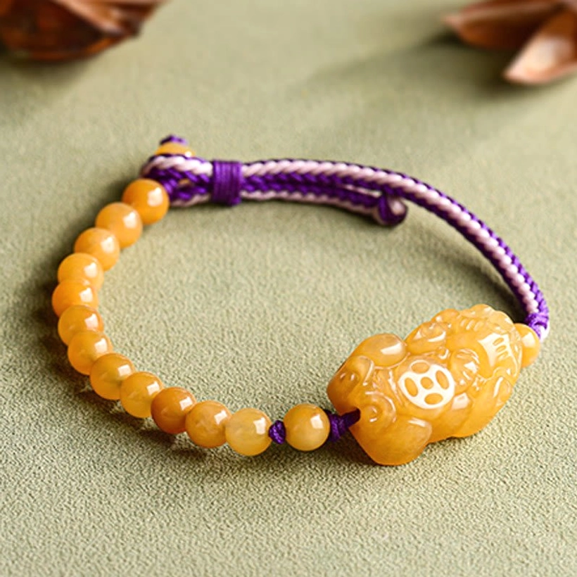 Golden Silk Jade Pi Xiu wealth bracelet full overhead view with blurred natural background