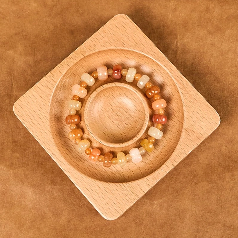 Golden Silk Jade prosperity bracelet arranged in wooden circular groove tray showing complete pumpkin bead strand
