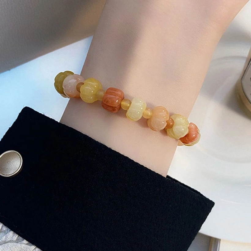 Golden Silk Jade barrel bead bracelet worn on wrist with black tailored sleeve showing smooth warm stone beads