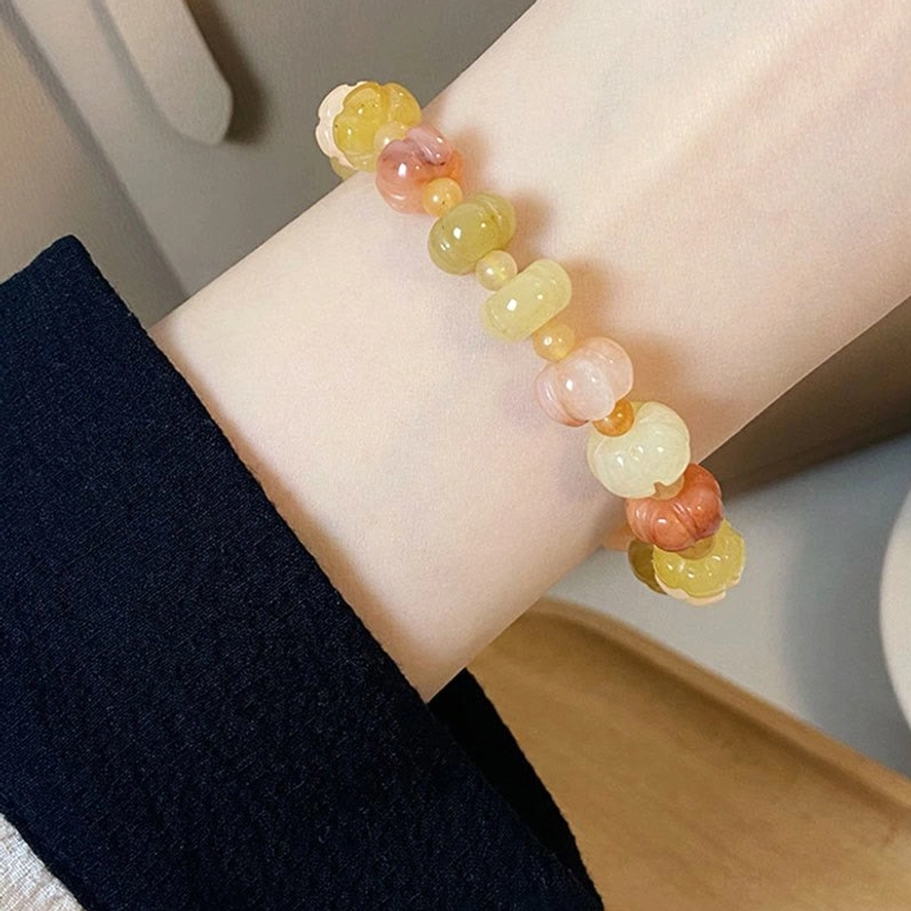 Golden Silk Jade pumpkin shaped bead bracelet worn on wrist with navy denim cuff showing gradient warm tones