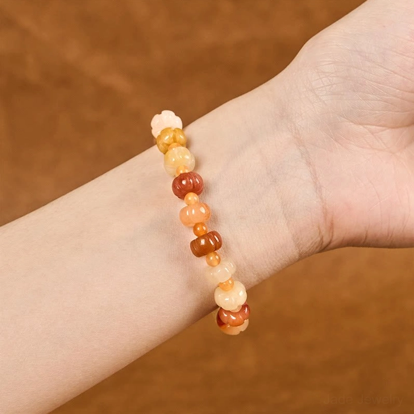 Golden Silk Jade jade pumpkin bracelet worn on wrist close-up showing warm barrel beads and natural striations