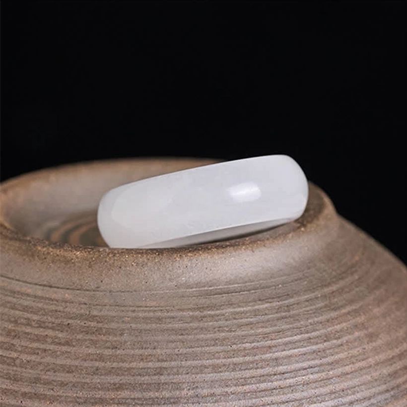 Natural golden silk jade ring placed on textured ceramic pottery bowl highlighting authentic jade material