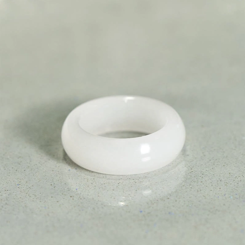 Natural golden silk jade ring flat lay top-down view on gray countertop displaying glossy finish and pure jade tone