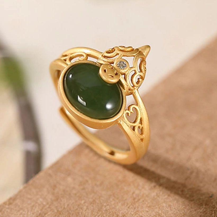 Gourd cyan jade copper coin ring full view hollow gold frame oblique angle