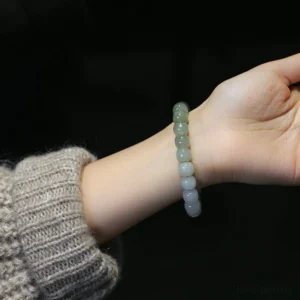 Gradient jade prosperity bracelet worn on wrist with knitted sweater background showing real-life wear and elegant styling